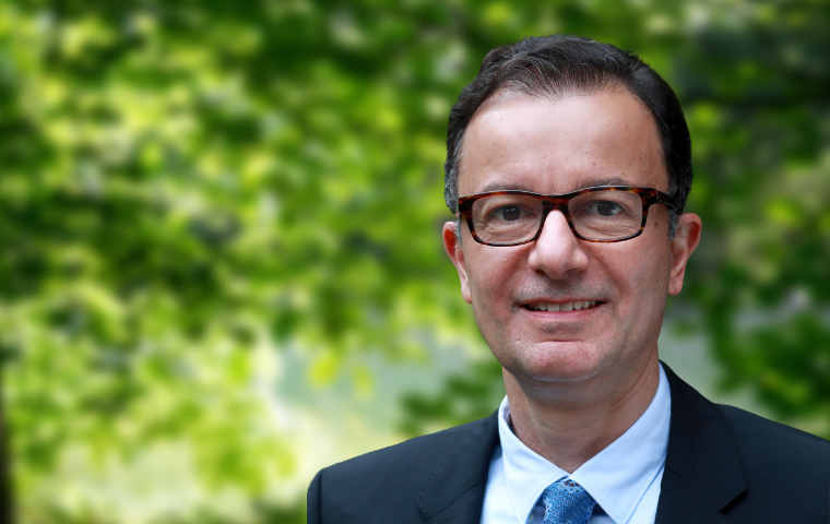 Wilson Garone in suit, standing in a wooded area.