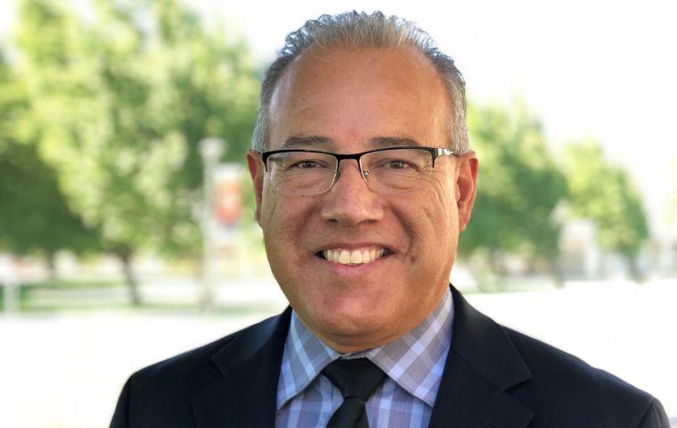 Raphael Espinosa III in a suit and tie, with a blurred out line of trees in the background.