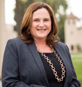 Sabrina Zirkel wearing a suit jacket, posed on Santa Clara's campus with the Mission Church in the far background. 