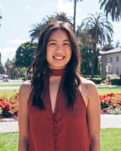 Megan Baldemor wearing dark orange shirt, standing on Palm Drive, facing away from Mission Church.