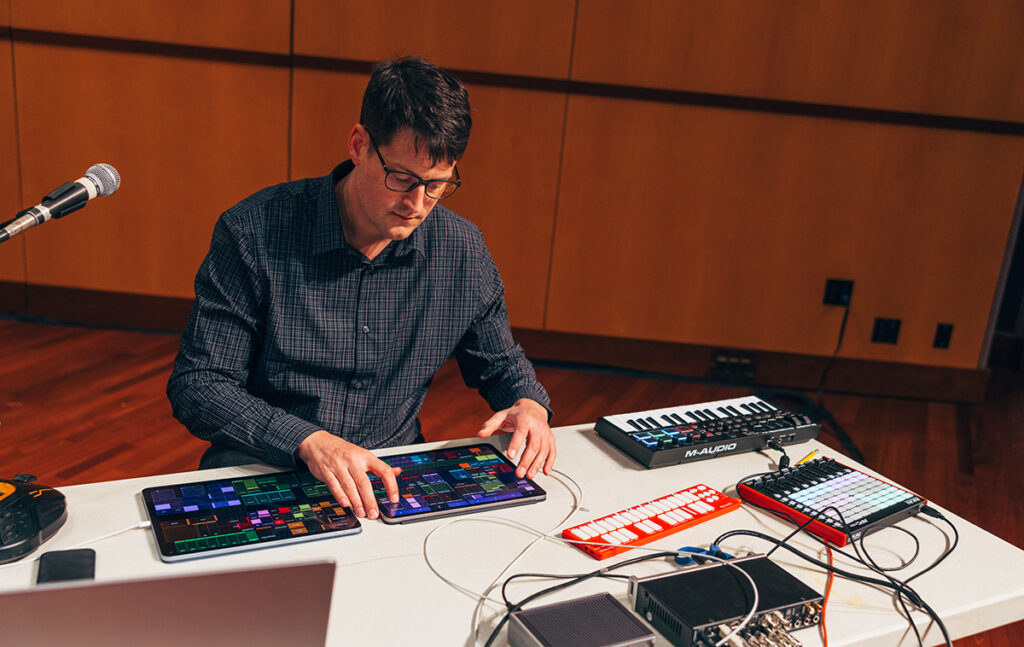 Sam pluta engages with several tablets and computer equipment to play music.