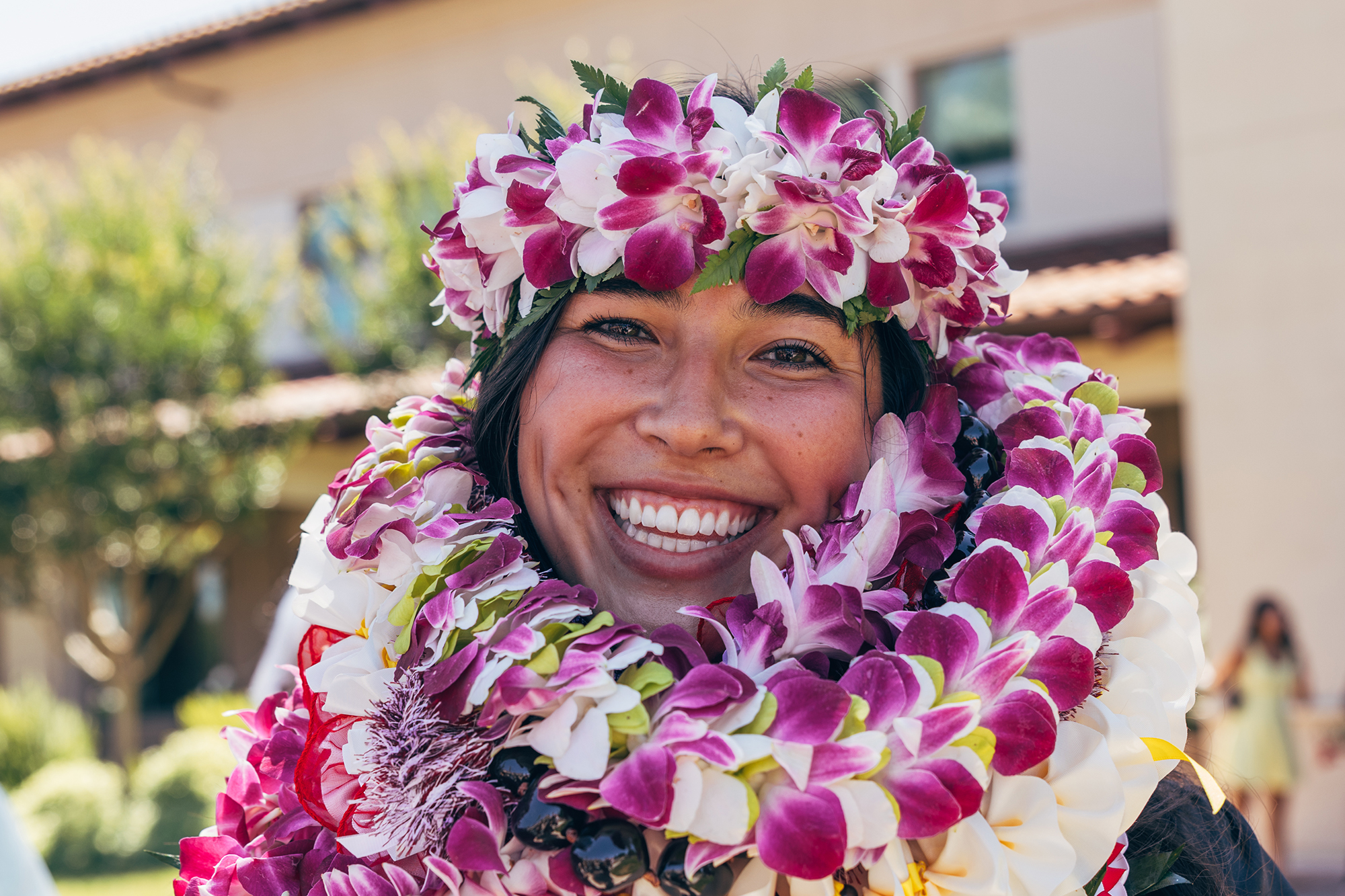 Young woman smiles as her head and shoulders are wrapped with Hawaiian leis.