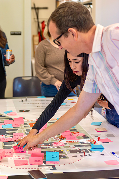 A professor and a student place colored sticky notes on a map of Santa Claras campus.