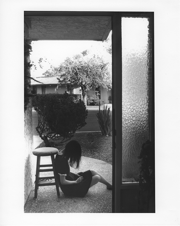 Elena Peng ’24 sitting in doorway with head down and hair falling over her face