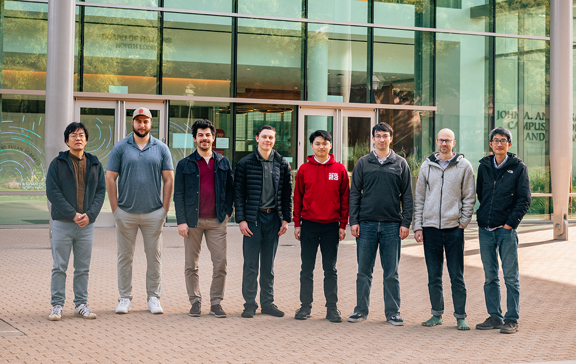 A row of students and research stand outside the Sobrato Campus for Innovation and Discovery.