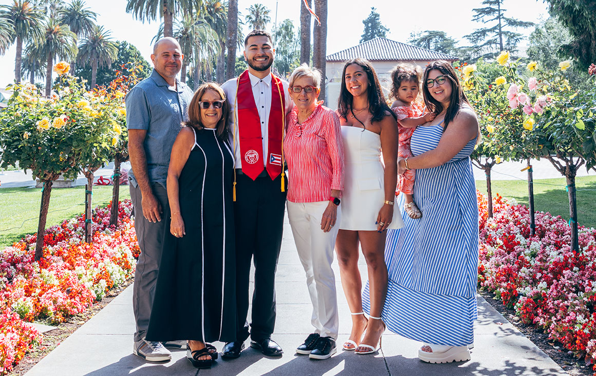 Roberto Mercado poses with his family and President Sullivan on campus.