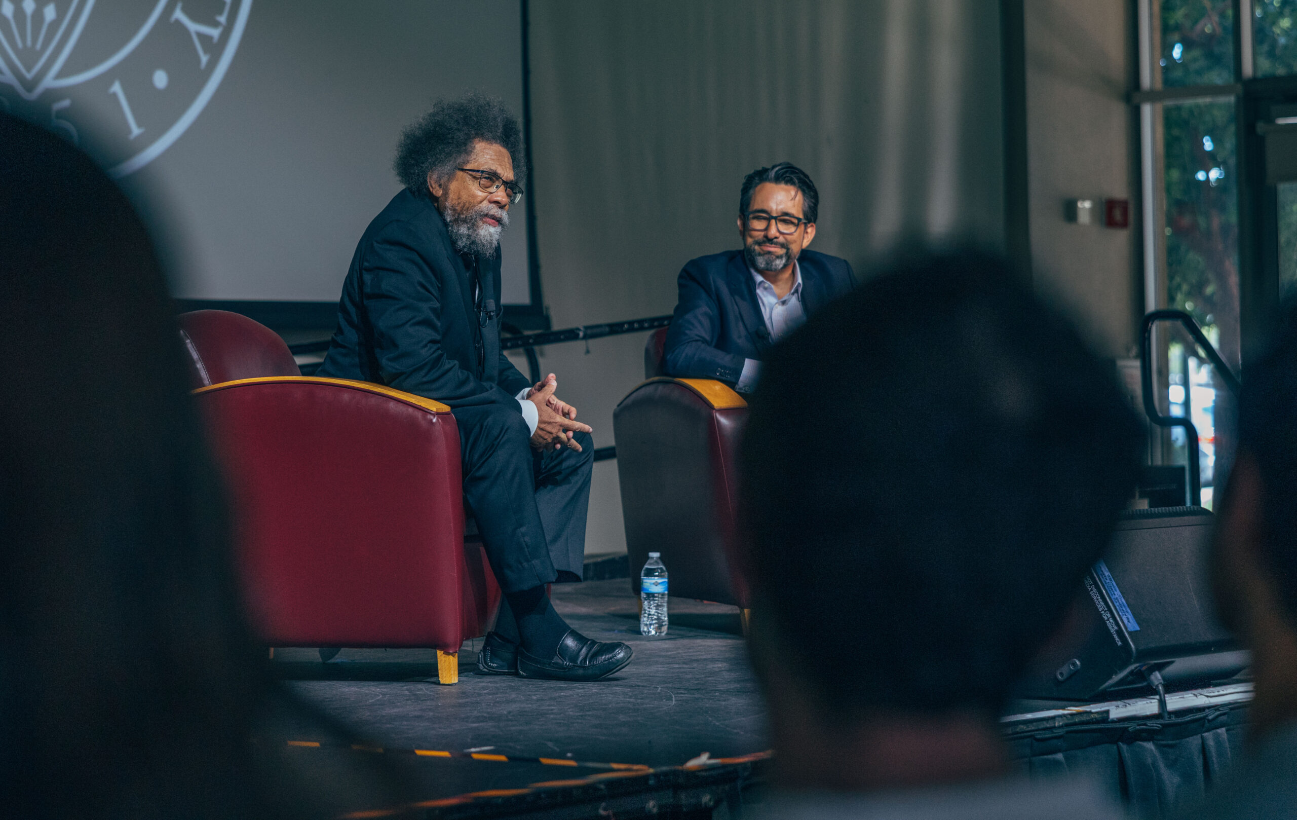 Two men converse on stage.