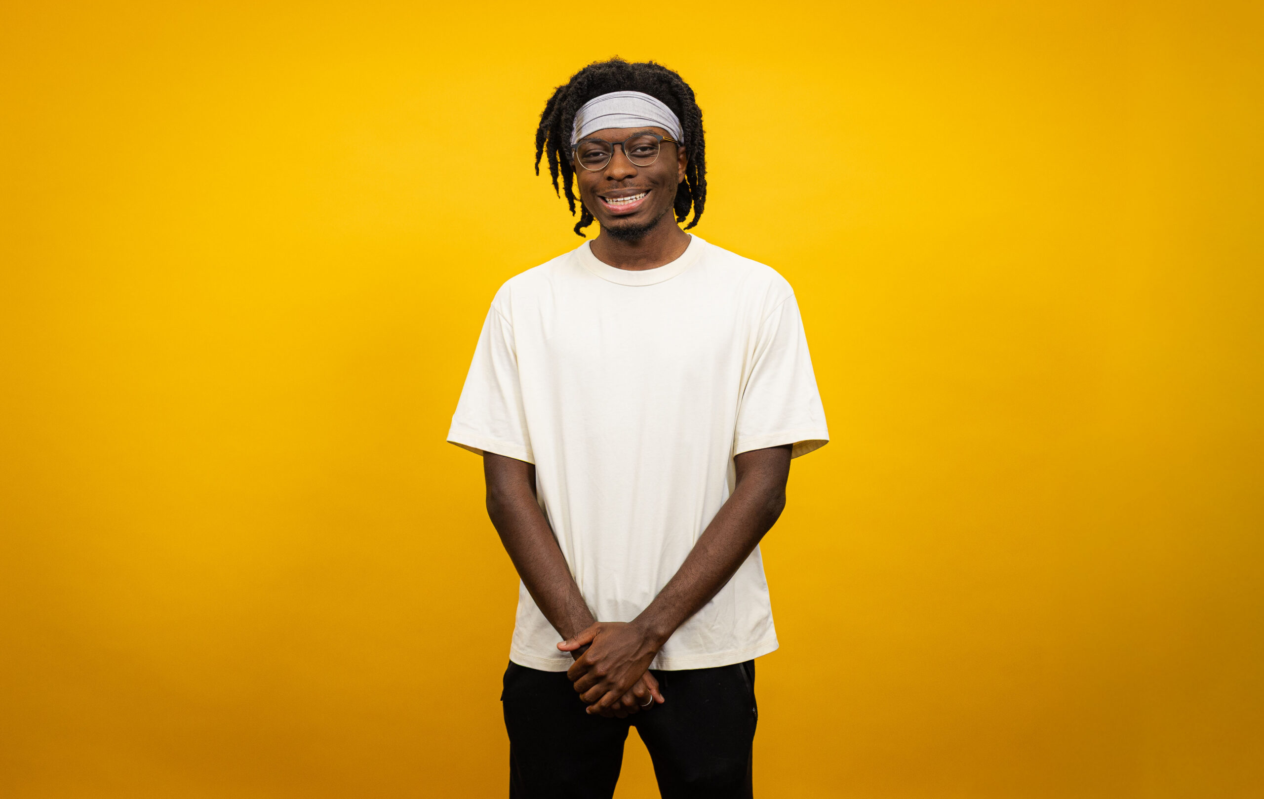 Young man stands in front of yellow backdrop.