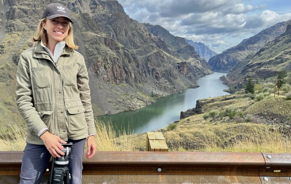 Woman in green jacke and baseball cap standing in front of Hells Canyon in Idaho