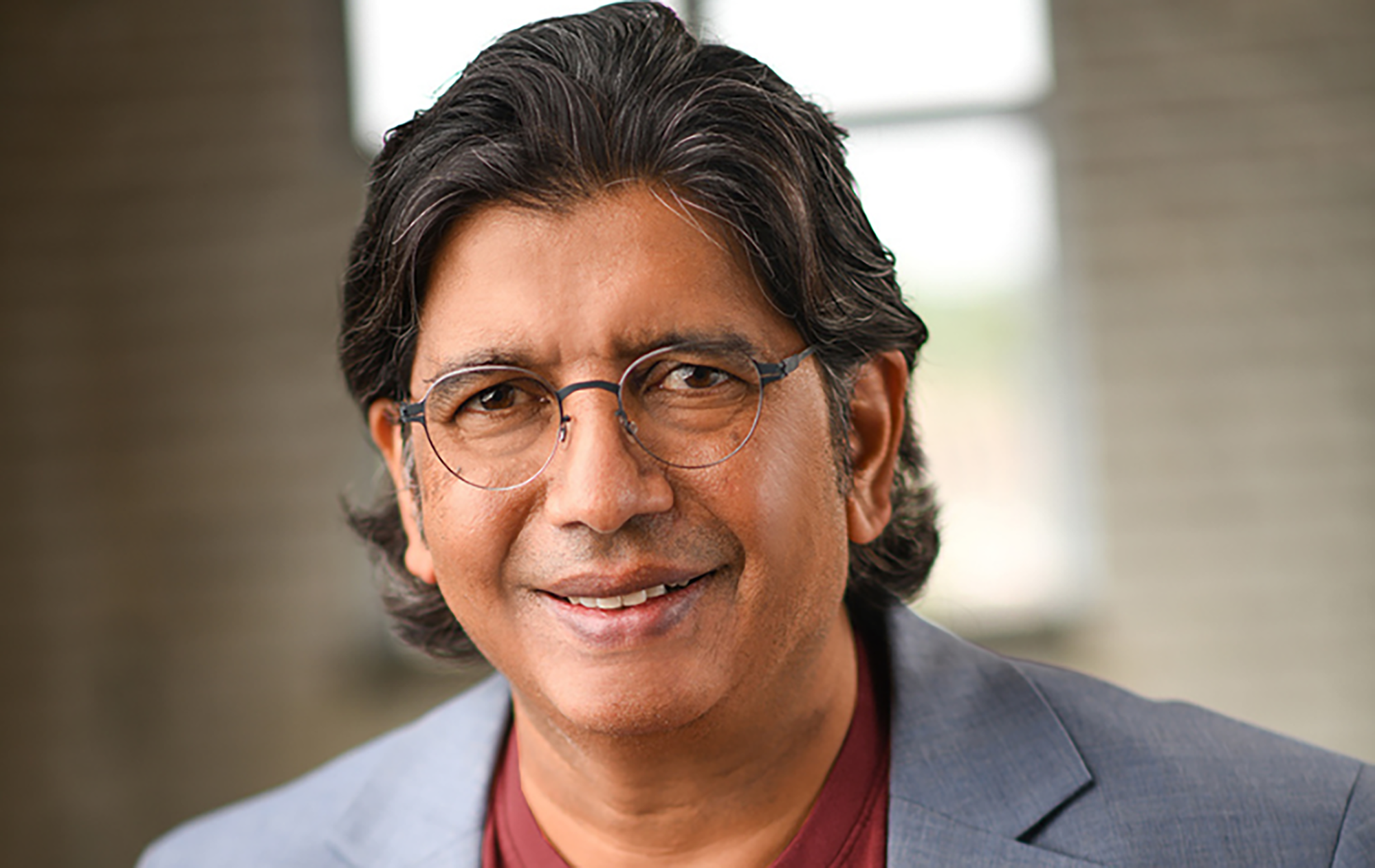 Ravi Bapna in gray suit and burgandy shirt